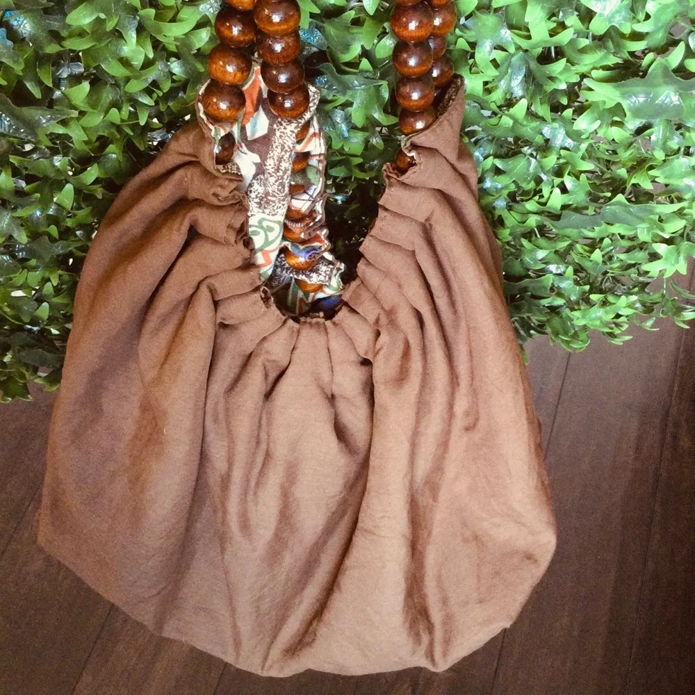 Reversible hobo tote with brown wood balls straps. Has a tie strap closu…
